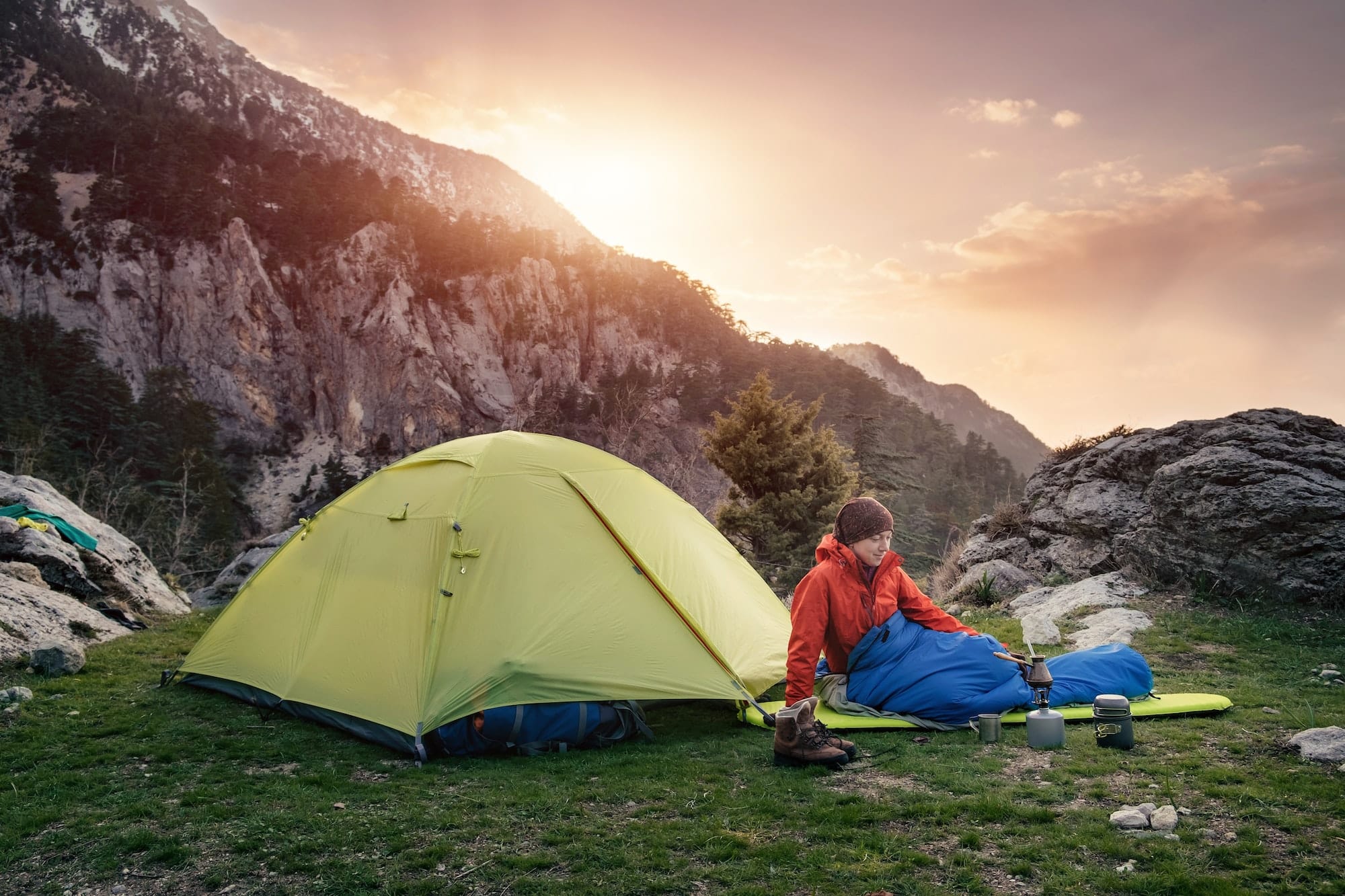 Female traveler in sleeping bag near the tent in the mountains