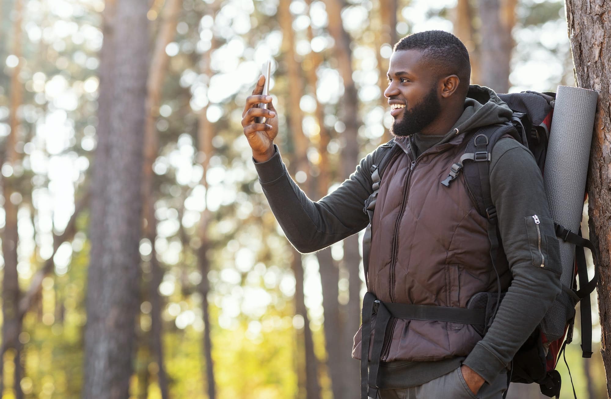 Happy black guy holding smartphone, finally got gps in woods